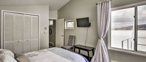 A hotel room with a bed, a chair, a small table, a TV, and a window with a view.