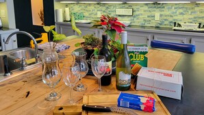 Eine Küchenarbeitsplatte mit Schneidebrett, Messer, Weingläsern, einer Flasche Sisham, einer Packung Club Cracker und einer Packung Sharp Cheddar Käse.