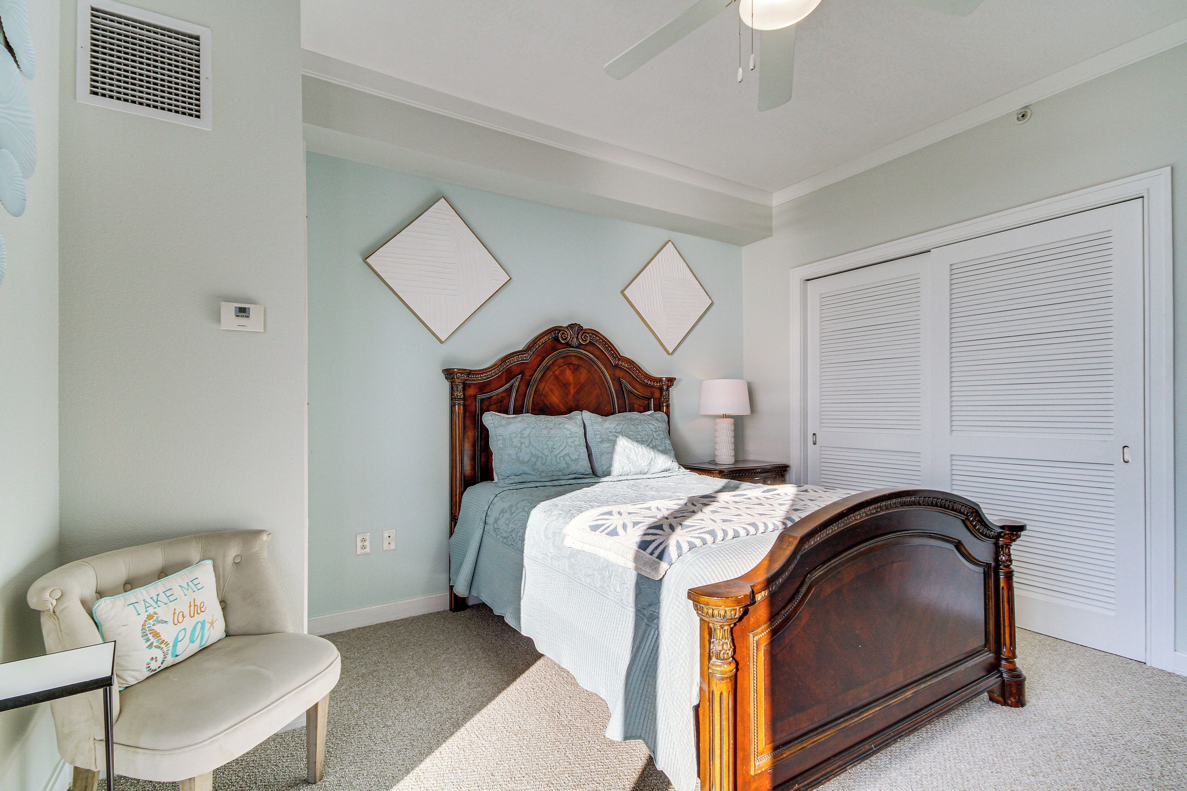 A bedroom with a bed, a chair, a nightstand, and a closet.