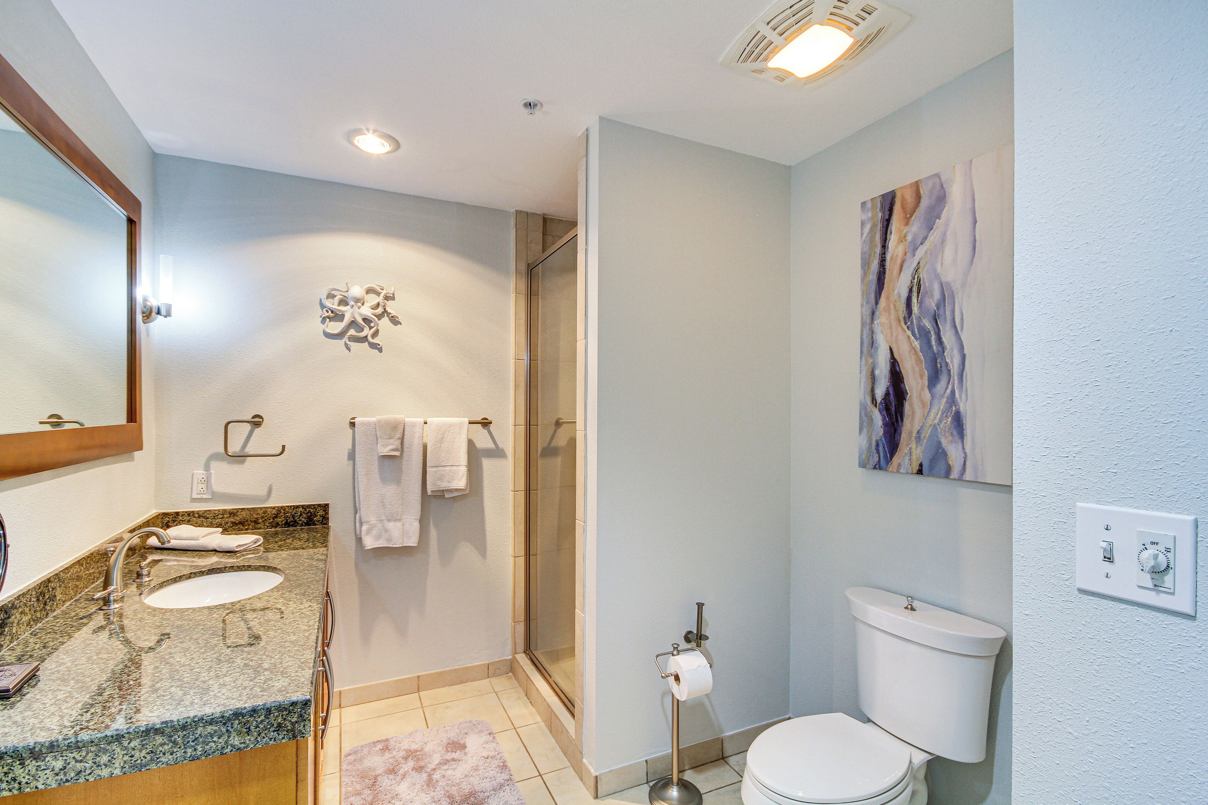 A modern bathroom with two sinks, a shower, and a toilet.