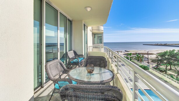 A balcony with wicker furniture, a glass table, and a view of the ocean. - Beachside Biloxi Club Condo: Balcony w/ Ocean View (Biloxi)