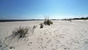 A sandy beach with footprints and sparse vegetation. - Beachside Biloxi Club Condo: Balcony w/ Ocean View (Biloxi)