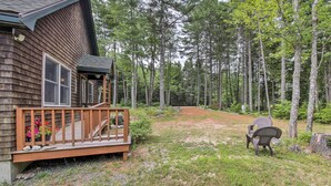 A wooden cabin with a deck, surrounded by a forest. - Hidden Gem Cottage' Near Blue Hill Peninsula (Brooklin)