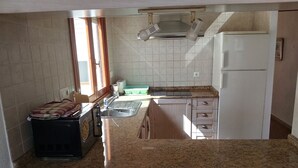 Une cuisine dotée d’un plan de travail en granit, d’une cuisinière encastrée, d’un évier et d’un réfrigérateur.