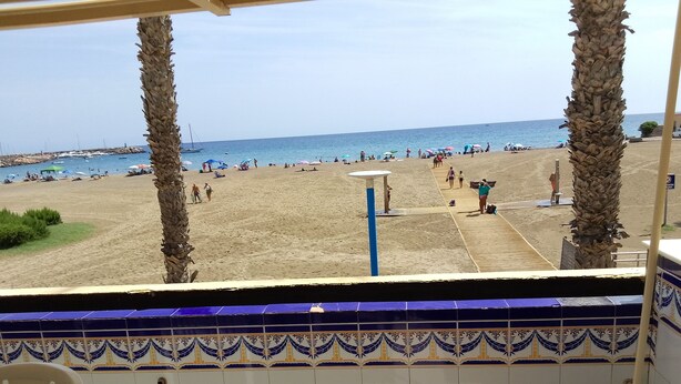 Une vue sur la plage depuis un espace abrité, doté de murs carrelés et d’une chaise.