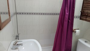 Une salle de bain avec un lavabo blanc, des toilettes et un rideau de douche.
