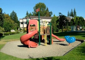 A playground with a slide, climbing area, and a blue fish-shaped structure.