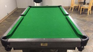 Une table de billard recouverte d’un drap de feutre vert et dotée d’un cadre en bois foncé.