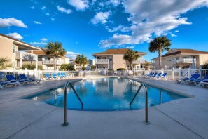 A swimming pool with blue lounge chairs, palm trees, and a clear blue sky. - < 1 Mi to Ocean: North Myrtle Beach Condo (North Myrtle Beach)