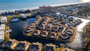 Un quartier résidentiel en bord de mer, doté d’un port de plaisance, de maisons à l’architecture uniforme et, au loin, d’un grand bâtiment d’hôtel.