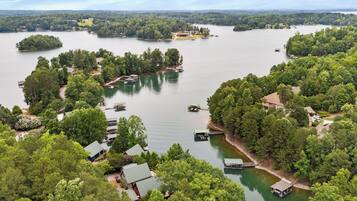 A lakeside property with multiple docks, boats, and houses surrounded by dense trees.