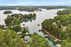 A lakeside property with multiple docks, boats, and houses surrounded by dense trees.