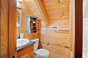 A wooden cabin bathroom with a sink, toilet, and mirror.