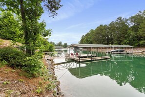 A tranquil lakeside setting with a dock, covered seating area, and a small pavilion.