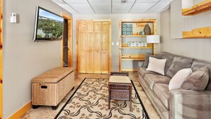 A living room with a sofa, a television mounted on the wall, a wooden wardrobe, a wicker bench, and a patterned rug. - Lakefront Keowee Home w/ Dock, 14 Mi to Clemson (Seneca)