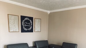 A corner living room with a black leather sectional sofa, a white coffee table, and three framed wall art pieces. - Hidden Gem Downtown Florence - Near UNA (Florence)