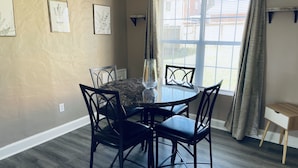 A dining area with a round table, four chairs, and a window with curtains. - Hidden Gem Downtown Florence - Near UNA (Florence)