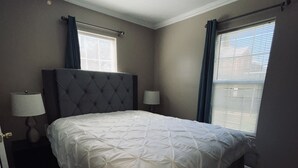A bedroom with a large bed, two bedside lamps, a window with blinds, and a ceiling light fixture. - Hidden Gem Downtown Florence - Near UNA (Florence)