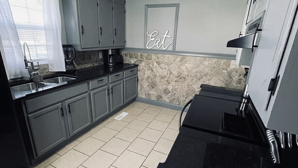 A kitchen with grey cabinets, a black countertop, and a backsplash. - Hidden Gem Downtown Florence - Near UNA (Florence)