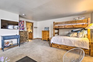 A bedroom with a bunk bed, a desk with a chair, a dresser, and a mirror.
