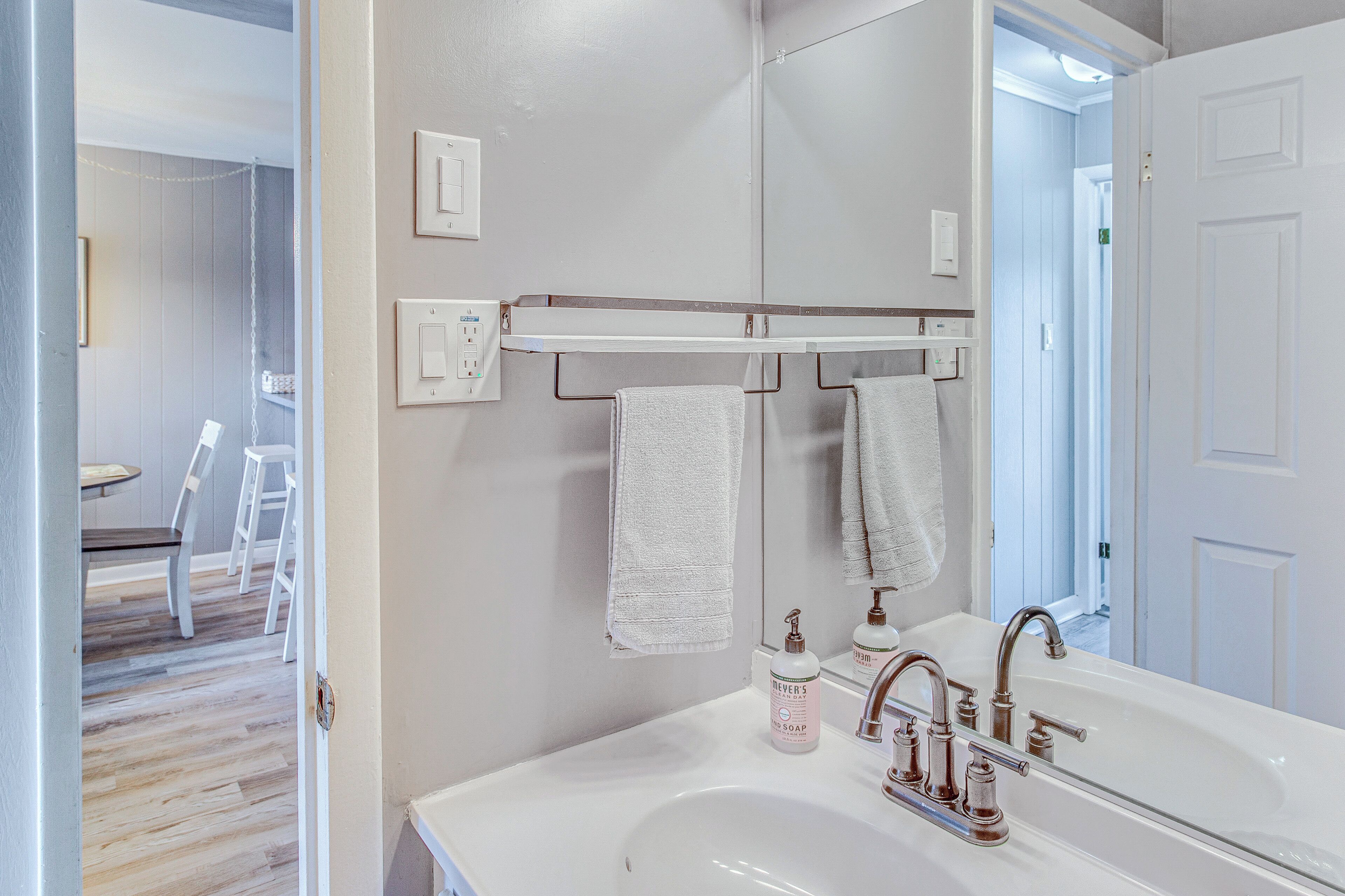 A bathroom with a white sink, a mirror, and a towel rack.