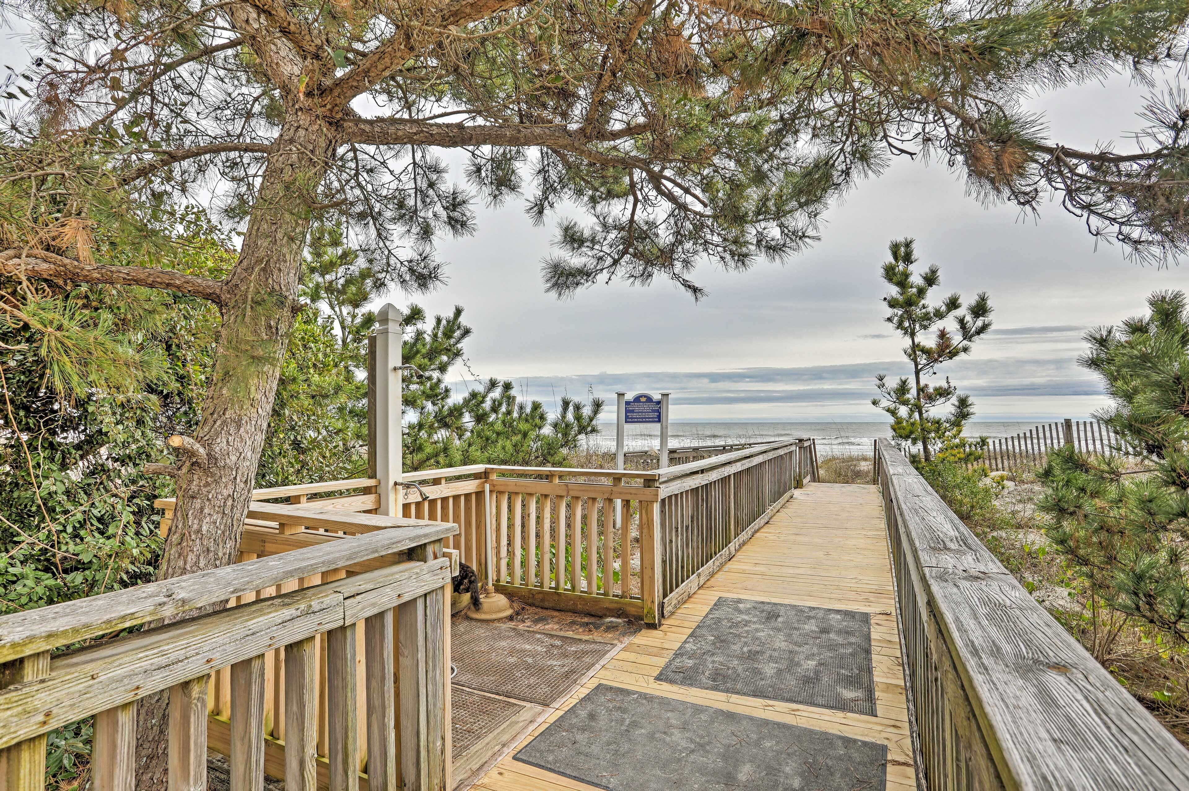 A wooden boardwalk leading to a beach with a view of the ocean.