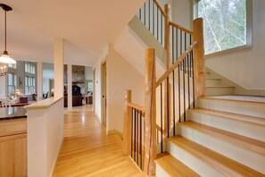 A spacious interior with a wooden staircase, a kitchen area, and a view through a window. - Home w/ Fire Pit, 7 Mi to Attitash Mtn Resort (Jackson)