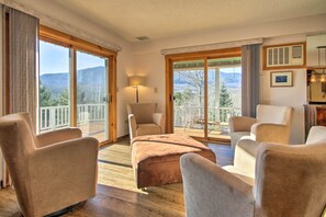 A spacious room with a large sliding glass door leading to a balcony with a mountain view. There are several plush armchairs and a sofa arranged around a central ottoman. - Hot Tub & Moat Mtn Views: North Conway Townhouse (North Conway)