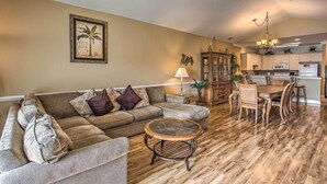 A living room with a sofa, a coffee table, and a dining area with chairs and a table. - 3 Mi to Beach & Golf: Resort Condo in Myrtle Beach (Myrtle Beach)
