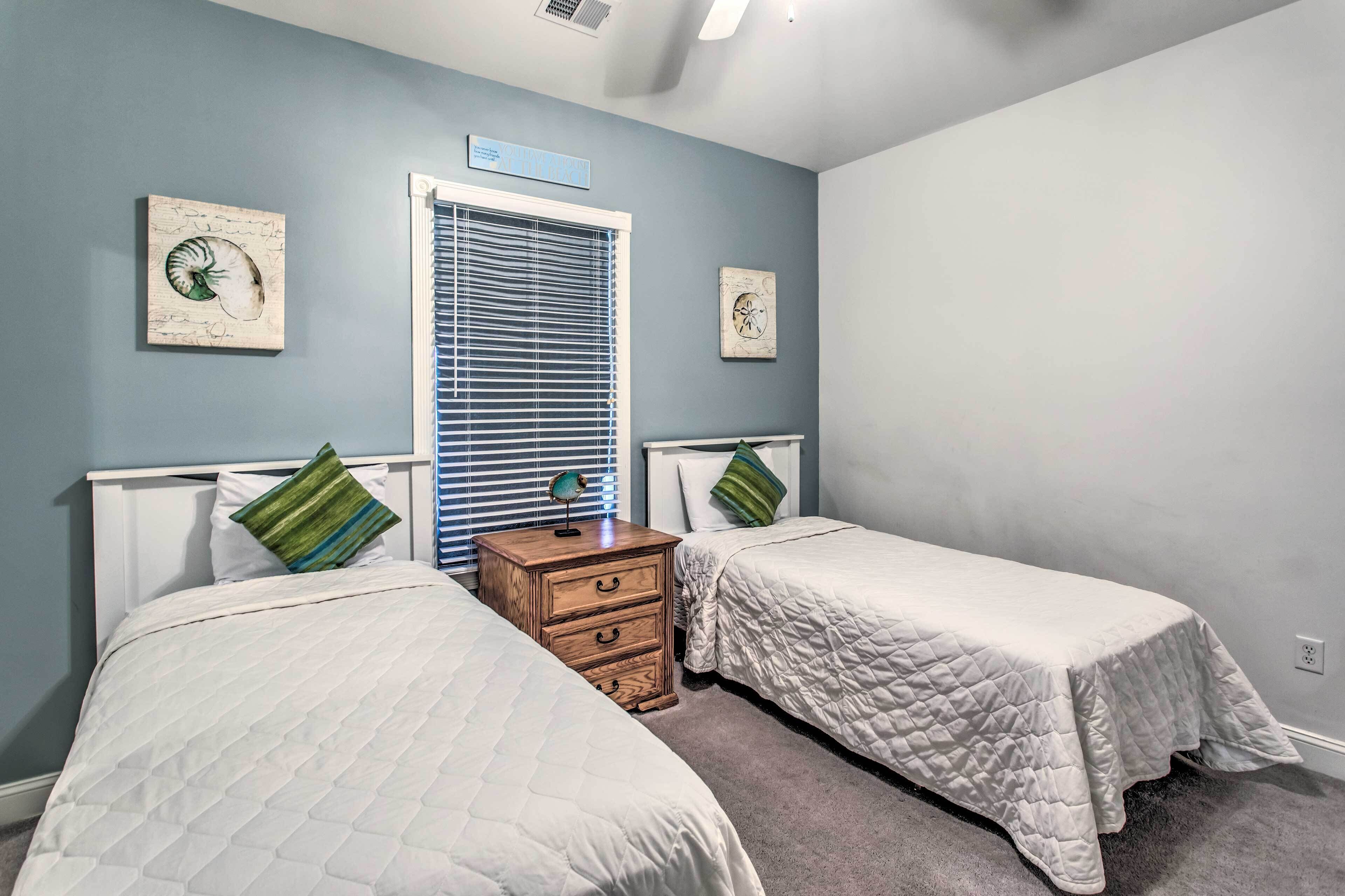 A bedroom with two beds, a nightstand, and a window with blinds.