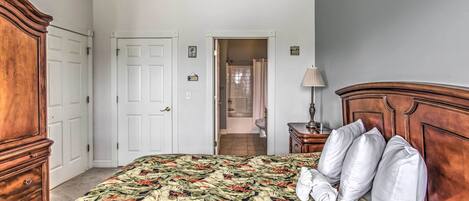A bedroom with a bed, wooden wardrobe, and a bathroom visible through an open door.