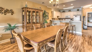 A dining area with a wooden table and chairs, a cabinet with glass doors, and a kitchen in the background. - 3 Mi to Beach & Golf: Resort Condo in Myrtle Beach (Myrtle Beach)