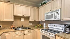 A kitchen with light wooden cabinets, a stainless steel sink, a microwave, a stove, and a coffee maker. - 3 Mi to Beach & Golf: Resort Condo in Myrtle Beach (Myrtle Beach)