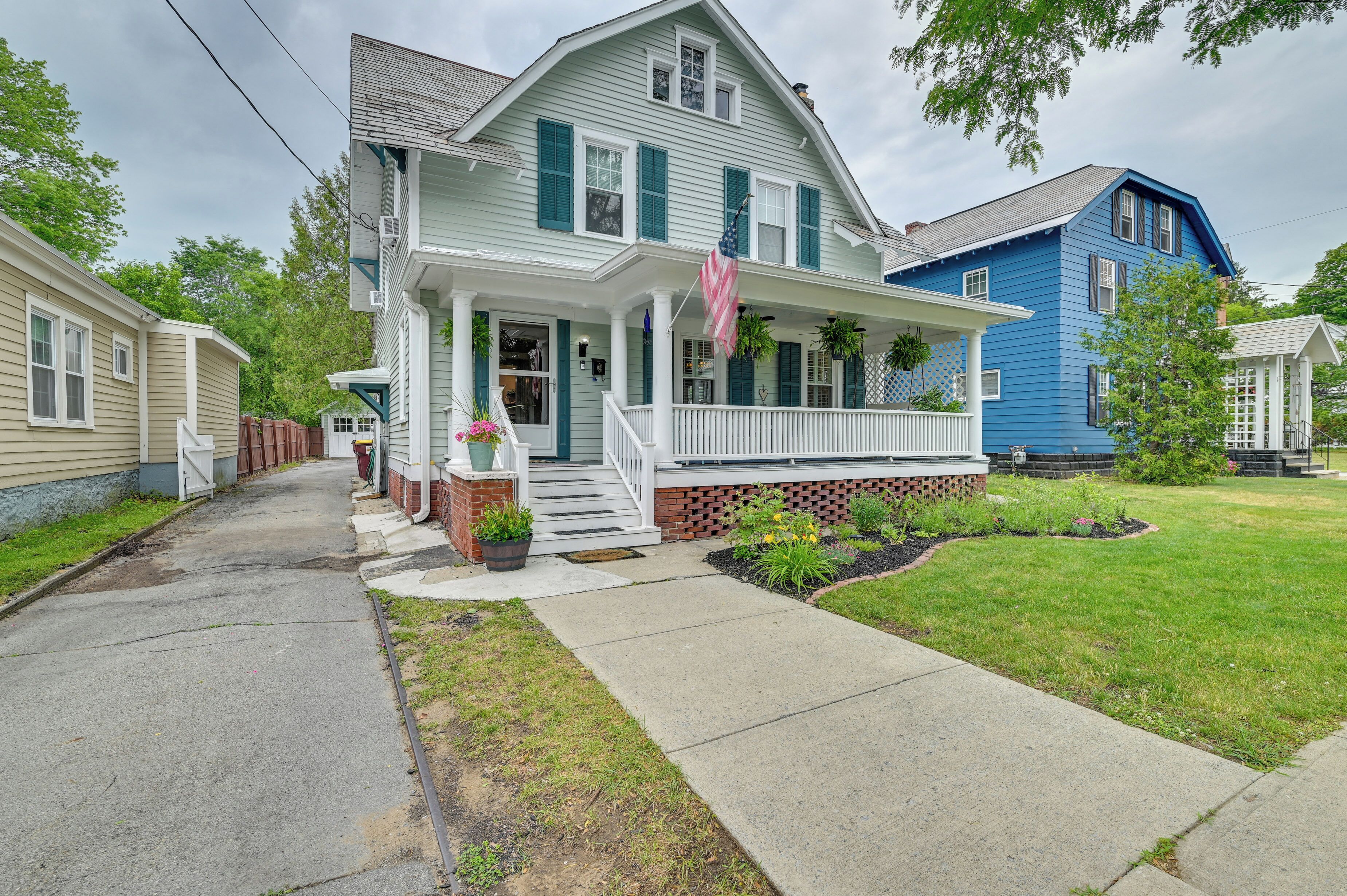 A two-story house with a front porch, a brick foundation, and a well-maintained lawn.