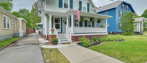 A two-story house with a front porch, a brick foundation, and a well-maintained lawn.