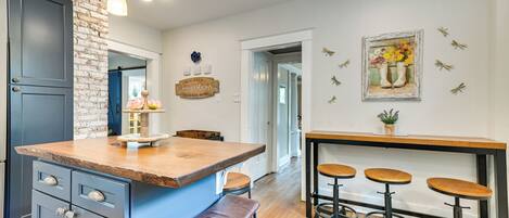 Una cocina con una isla azul, taburetes de madera y una pared de ladrillo decorativa.