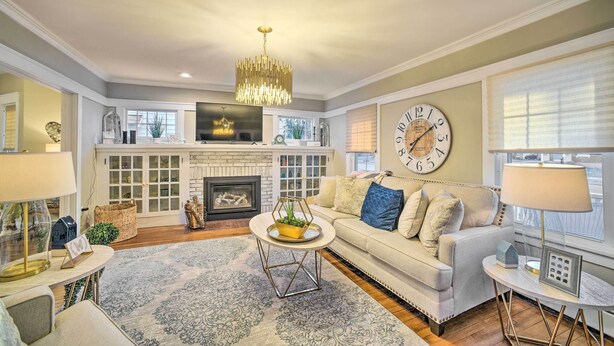 A living room with a fireplace, a sofa, a coffee table, and a chandelier. - Family-friendly Glens Falls Home w/ Sun Porch (Glens Falls)