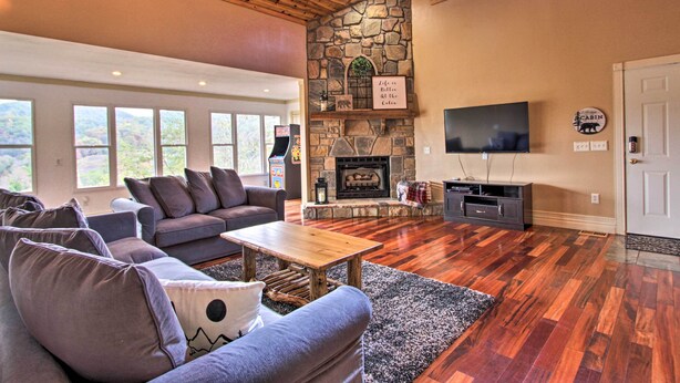 A spacious living room with a stone fireplace, a large TV, and comfortable seating. - Luxe Cabin w/ Covered Pool + Smoky Mountain Vistas (Sevierville)