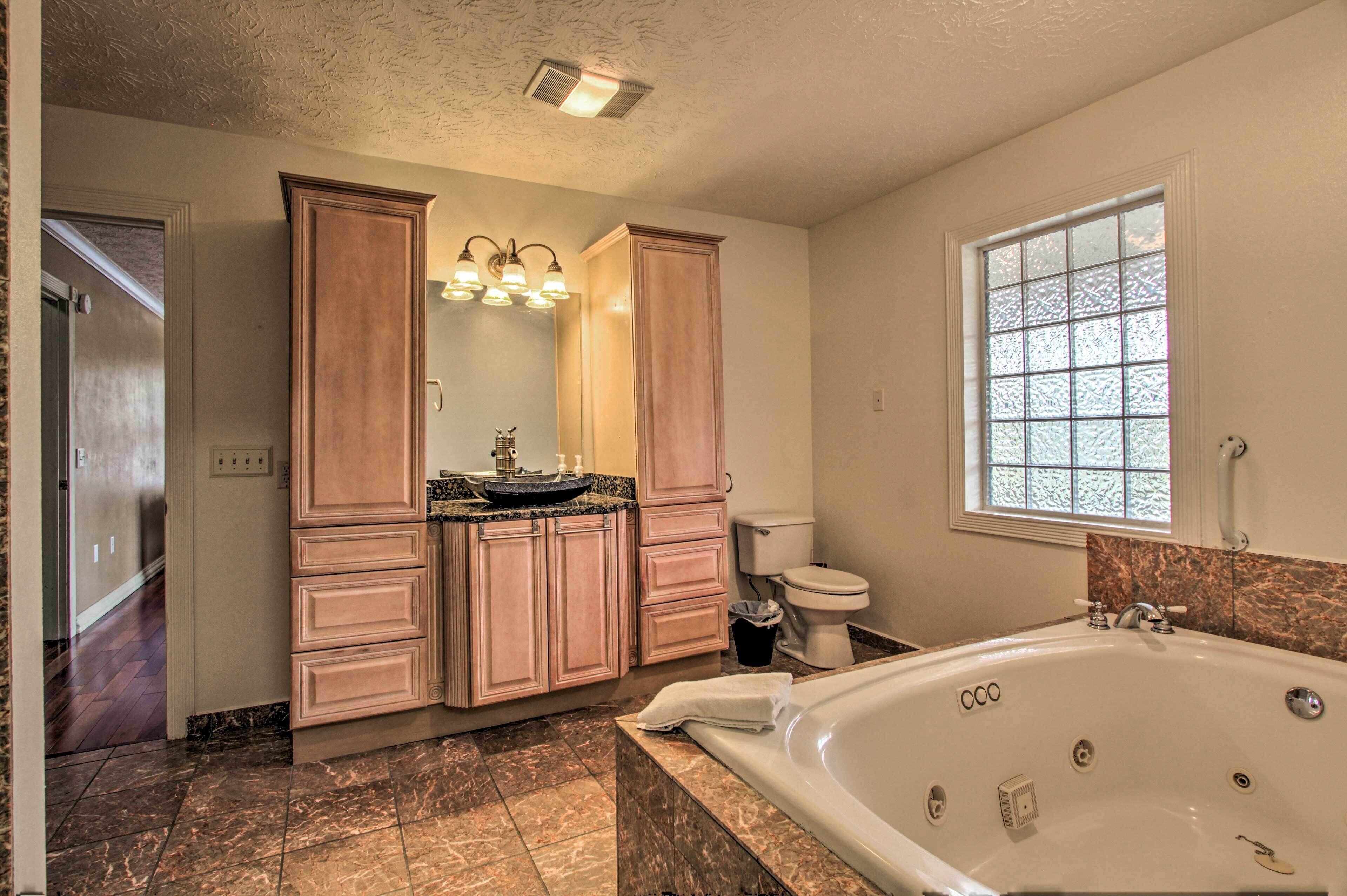 A bathroom with a bathtub, vanity with a sink, and a toilet.