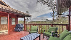 A wooden deck with green chairs and a table, overlooking a natural landscape. - Luxe Cabin w/ Covered Pool + Smoky Mountain Vistas (Sevierville)