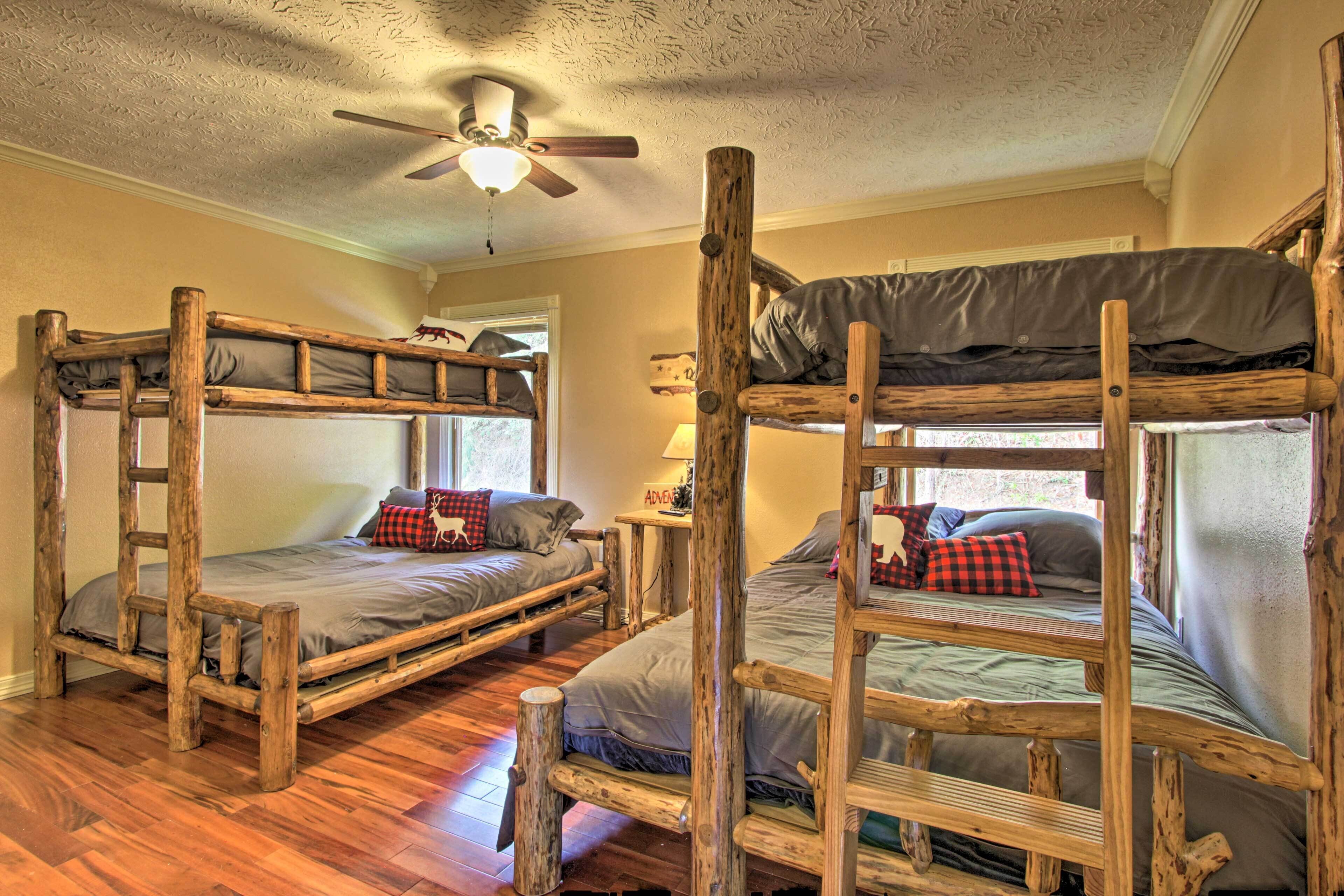 Una habitación con tres literas de madera, un ventilador de techo y una ventana con vistas.