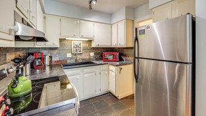 Una cucina moderna con mobili bianchi, elettrodomestici in acciaio inossidabile e un piano di lavoro in granito.