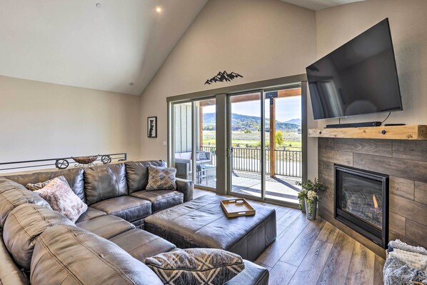 A modern living room with a sectional sofa, a flat-screen TV, and a fireplace.