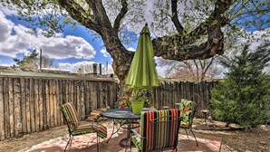 A patio with a round table and chairs, a green umbrella, and a wooden fence. - 1 Mi to Santa Fe Plaza: Quiet Home w/ Patio (Santa Fe)