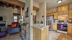 A spacious living room with a fireplace, a kitchen with wooden cabinets, and a built-in island. - 1 Mi to Santa Fe Plaza: Quiet Home w/ Patio (Santa Fe)