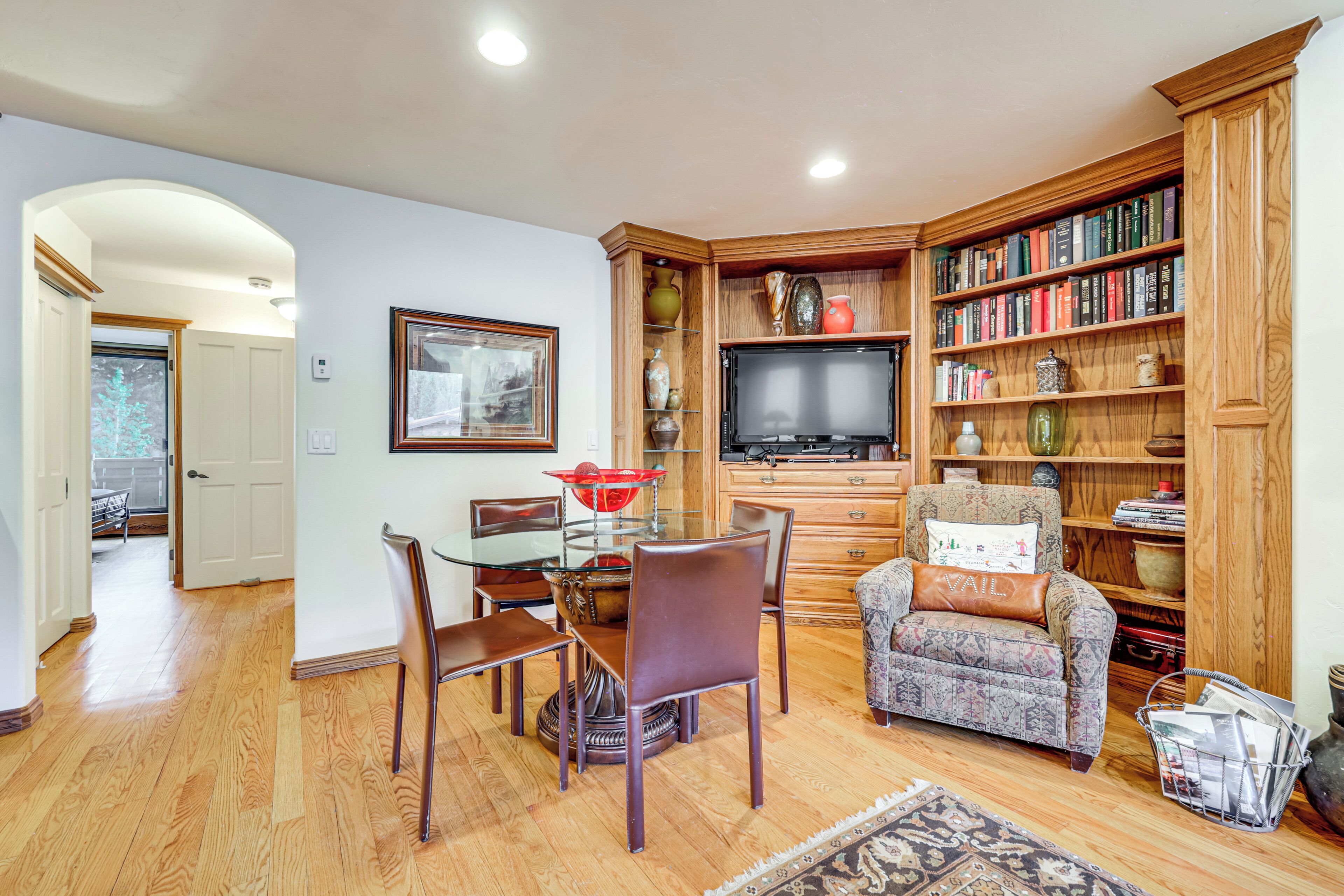 A living room with a dining table, chairs, a television, a bookshelf, and a fireplace.