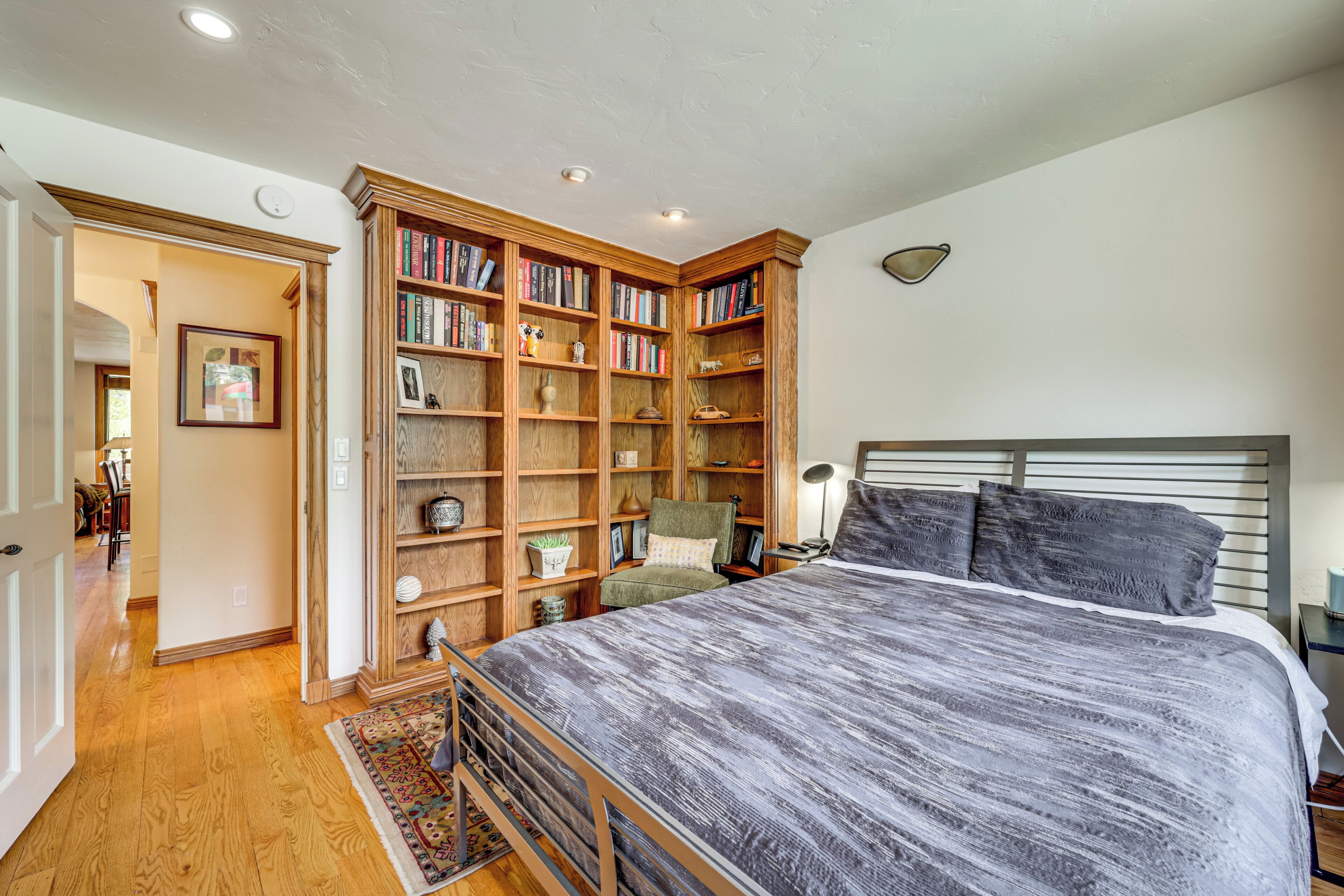 Quarto com cama grande, estantes de madeira, escrivaninha e uma cadeira.