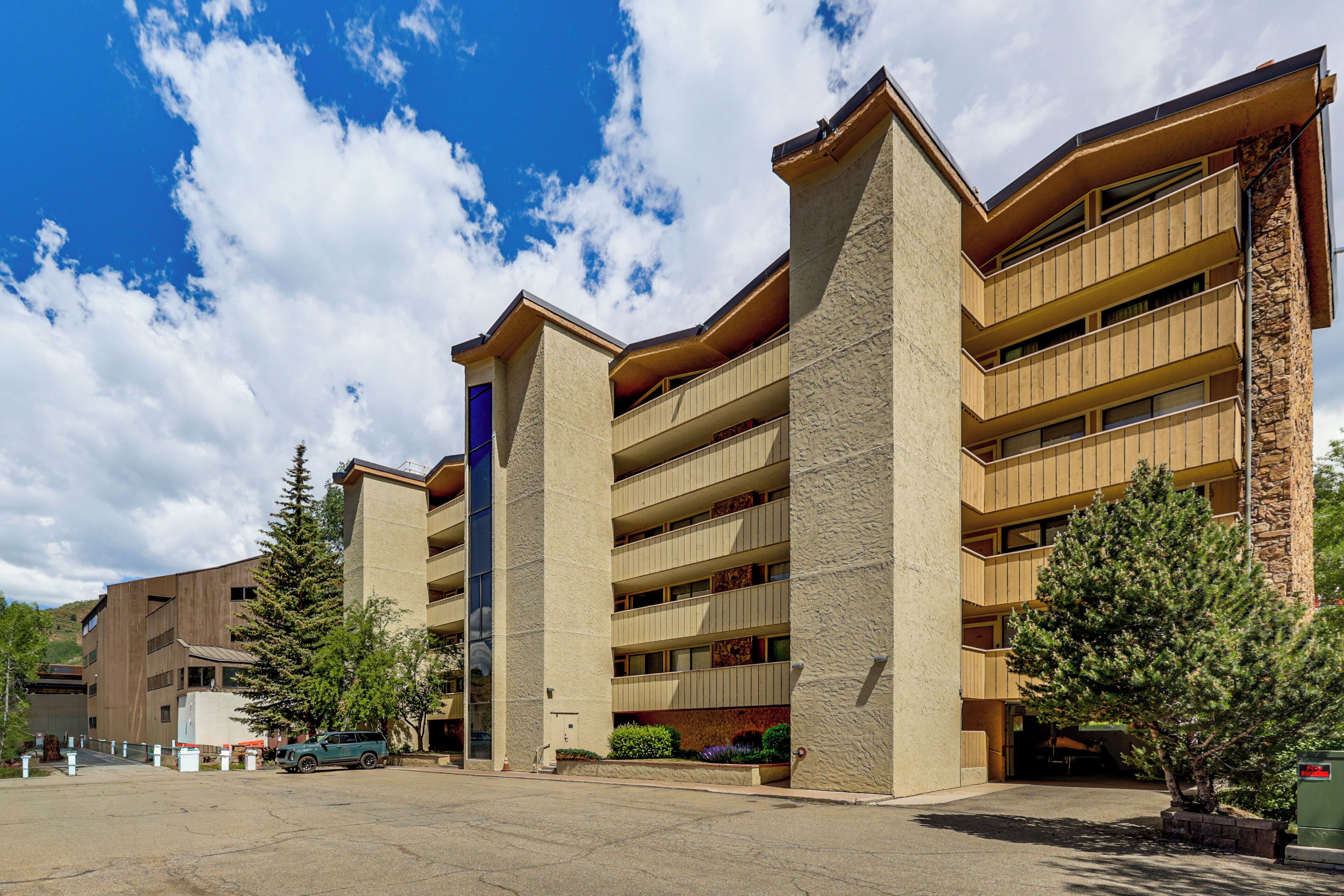 A multi-story building with a parking lot in front.