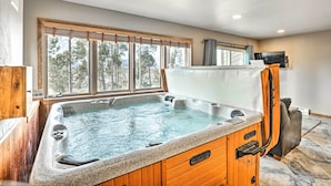 Un jacuzzi en una habitación con un ventanal grande, paredes de madera y un televisor en la pared.