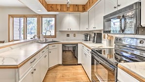 Una cocina moderna con armarios blancos, estufa de acero inoxidable y lavavajillas.